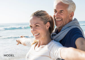 Older Couple with Nice Teeth Holding Arms Out at Beach
